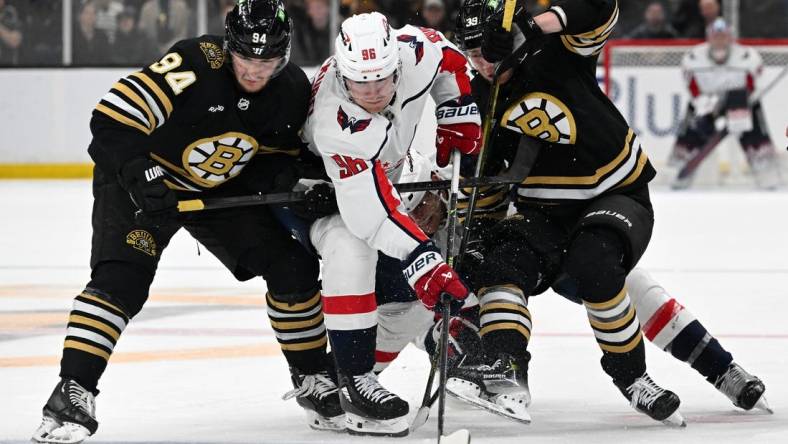 Feb 10, 2024; Boston, Massachusetts, USA; Washington Capitals right wing Nicolas Aube-Kubel (96) battles for the puck against Boston Bruins center Jakub Lauko (94) and center Morgan Geekie (39) during the second period at the TD Garden. Mandatory Credit: Brian Fluharty-USA TODAY Sports