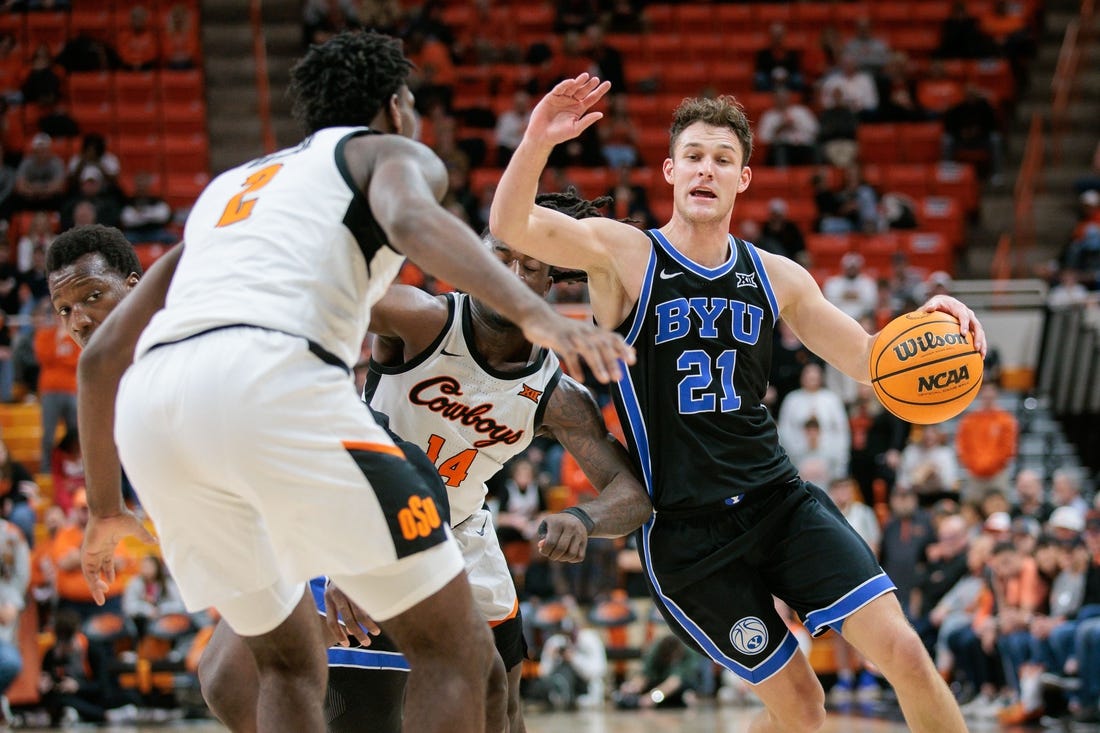 Feb 17, 2024; Stillwater, Oklahoma, USA; Brigham Young Cougars guard Trevin Knell (21) drives to the basket around Oklahoma State Cowboys guard Jamyron Keller (14) and Oklahoma State Cowboys forward Eric Dailey Jr. (2) during the second half at Gallagher-Iba Arena. Mandatory Credit: William Purnell-USA TODAY Sports