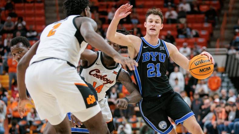 Feb 17, 2024; Stillwater, Oklahoma, USA; Brigham Young Cougars guard Trevin Knell (21) drives to the basket around Oklahoma State Cowboys guard Jamyron Keller (14) and Oklahoma State Cowboys forward Eric Dailey Jr. (2) during the second half at Gallagher-Iba Arena. Mandatory Credit: William Purnell-USA TODAY Sports