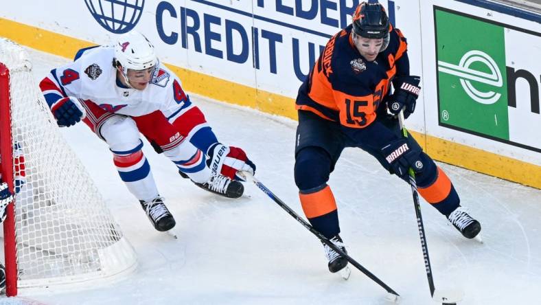 Feb 18, 2024; East Rutherford, New Jersey, USA;  New York Islanders right wing Cal Clutterbuck (15) skates with the puck defended by New York Rangers defenseman Braden Schneider (4) during the first period in a Stadium Series ice hockey game at MetLife Stadium. Mandatory Credit: Dennis Schneidler-USA TODAY Sports