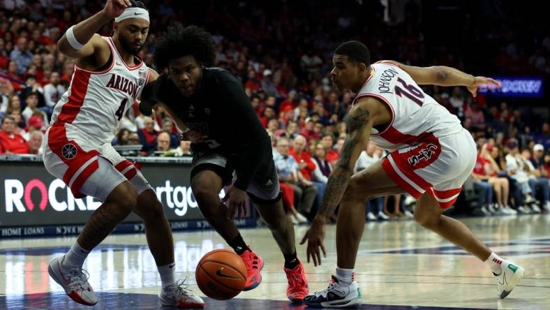 Feb 24, 2024; Tucson, Arizona, USA; Washington Huskies guard Sahvir Wheeler (5) drives to the net against Arizona Wildcats guard Kylan Boswell (4) and forward Keshad Johnson (16) during the first half at McKale Center. Mandatory Credit: Zachary BonDurant-USA TODAY Sports