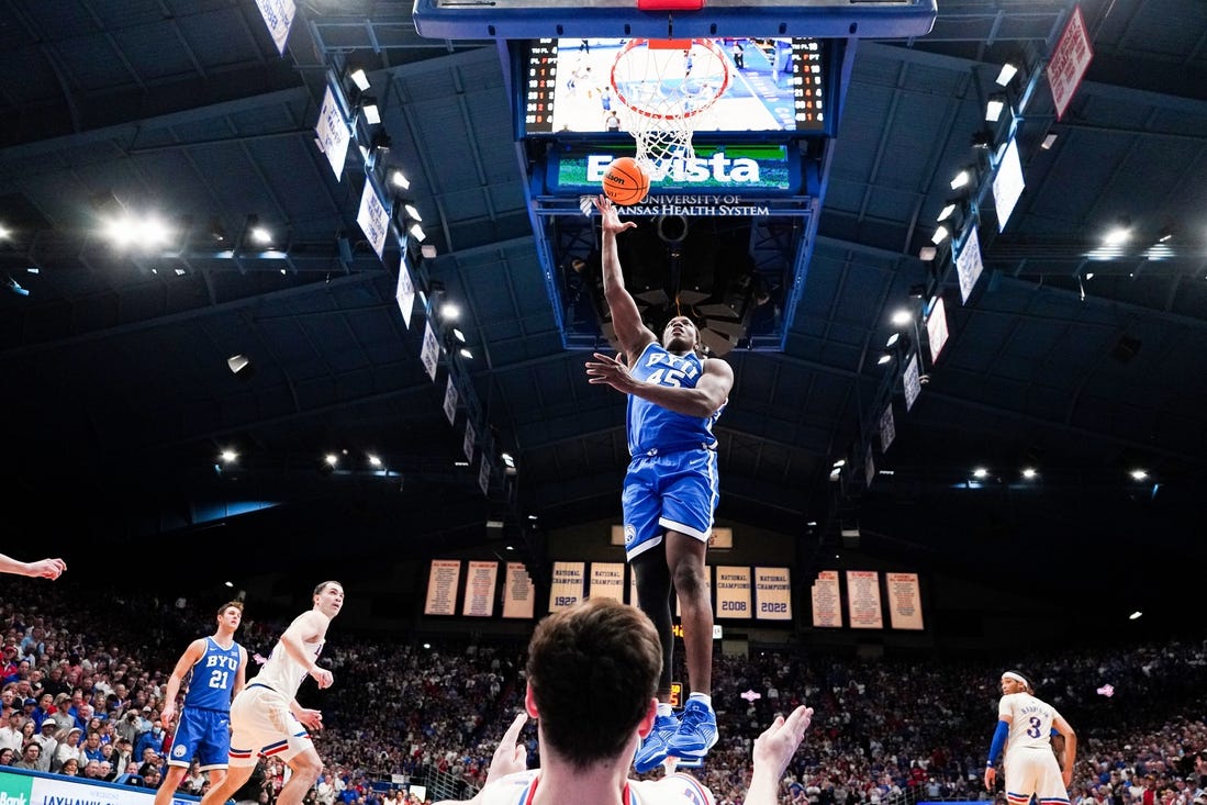 Feb 27, 2024; Lawrence, Kansas, USA; Brigham Young Cougars forward Fousseyni Traore (45) shoots as Kansas Jayhawks forward Parker Braun (23) falls below him during the second half at Allen Fieldhouse. Mandatory Credit: Denny Medley-USA TODAY Sports