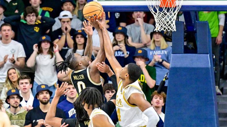 Feb 27, 2024; South Bend, Indiana, USA; Wake Forest Demon Deacons guard Kevin Miller (0) goes up for a shot as Notre Dame Fighting Irish forward Kebba Njie (14) defends in the second half at the Purcell Pavilion. Mandatory Credit: Matt Cashore-USA TODAY Sports