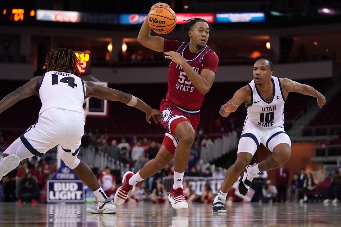 Feb 27, 2024; Fresno, California, USA; Fresno State Bulldogs guard Xavier DuSell (53) drives past Utah State Aggies guard Josh Uduje (14) and guard Darius Brown II (10) in overtime at the Save Mart Center. Mandatory Credit: Cary Edmondson-USA TODAY Sports