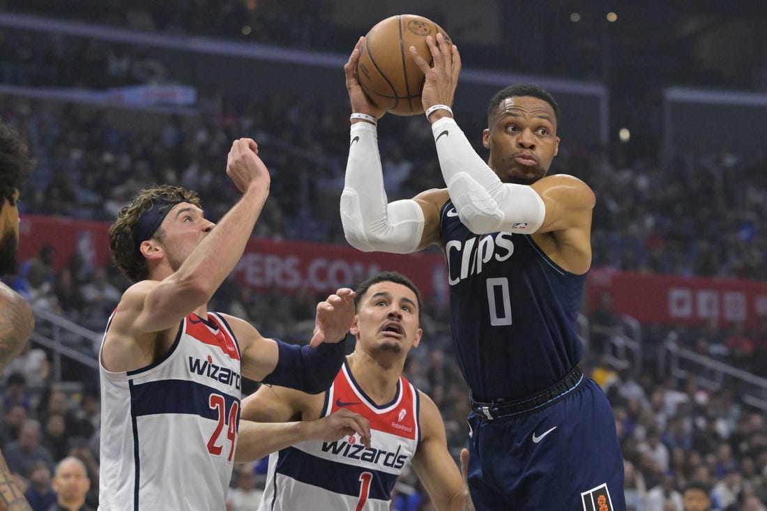 Mar 1, 2024; Los Angeles, California, USA; Los Angeles Clippers guard Russell Westbrook (0) passes the ball as he is defended by Washington Wizards forward Corey Kispert (24) and guard Johnny Davis (1) in the first half at Crypto.com Arena. Mandatory Credit: Jayne Kamin-Oncea-USA TODAY Sports