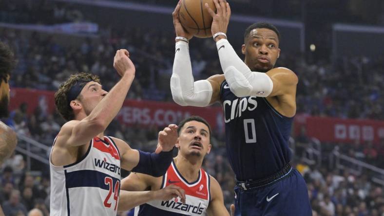 Mar 1, 2024; Los Angeles, California, USA; Los Angeles Clippers guard Russell Westbrook (0) passes the ball as he is defended by Washington Wizards forward Corey Kispert (24) and guard Johnny Davis (1) in the first half at Crypto.com Arena. Mandatory Credit: Jayne Kamin-Oncea-USA TODAY Sports