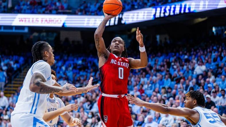 Mar 2, 2024; Chapel Hill, North Carolina, USA; North Carolina State Wolfpack guard DJ Horne (0) shoots between North Carolina Tar Heels forward Armando Bacot (5) (left) and forward Harrison Ingram (55) during the first half at Dean E. Smith Center. Mandatory Credit: Scott Kinser-USA TODAY Sports