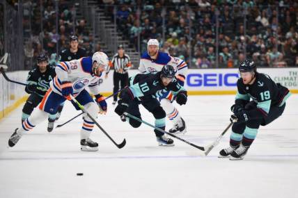 Mar 2, 2024; Seattle, Washington, USA; Edmonton Oilers center Leon Draisaitl (29) and Seattle Kraken center Matty Beniers (10) and left wing Jared McCann (19) chase the puck during the second period at Climate Pledge Arena. Mandatory Credit: Steven Bisig-USA TODAY Sports