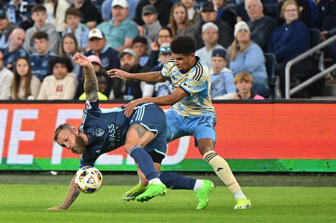 Mar 2, 2024; Kansas City, Kansas, USA; Sporting Kansas City forward Johnny Russell (7) battles Philadelphia Union defender Nathan Harriel (26) for the ball in the first half at Children's Mercy Park. Mandatory Credit: Peter Aiken-USA TODAY Sports