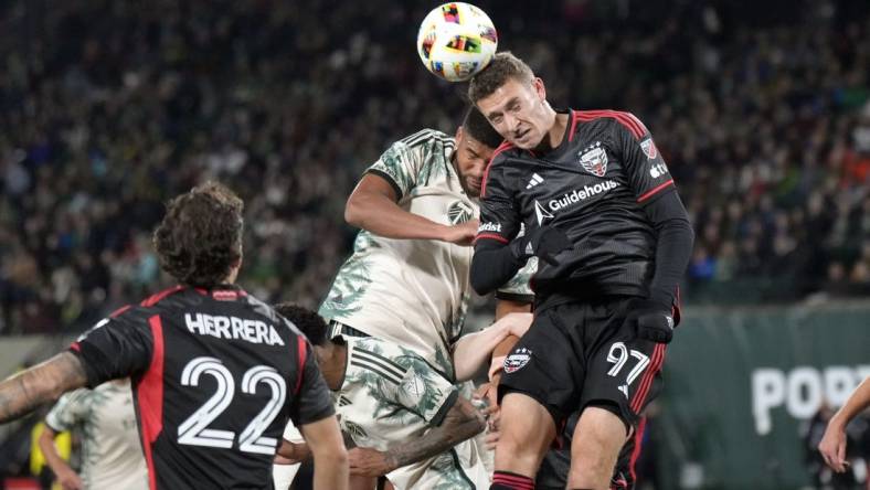 Mar 2, 2024; Portland, Oregon, USA; D.C. United defender Christopher McVey (97) heads a ball against Portland Timbers defender Zachery McGraw (18, left) during the first half at Providence Park. Mandatory Credit: Soobum Im-USA TODAY Sports