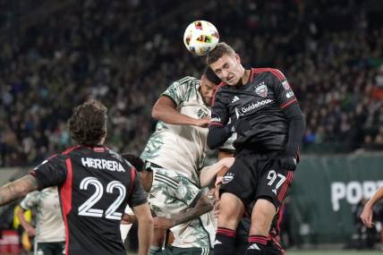 Mar 2, 2024; Portland, Oregon, USA; D.C. United defender Christopher McVey (97) heads a ball against Portland Timbers defender Zachery McGraw (18, left) during the first half at Providence Park. Mandatory Credit: Soobum Im-USA TODAY Sports
