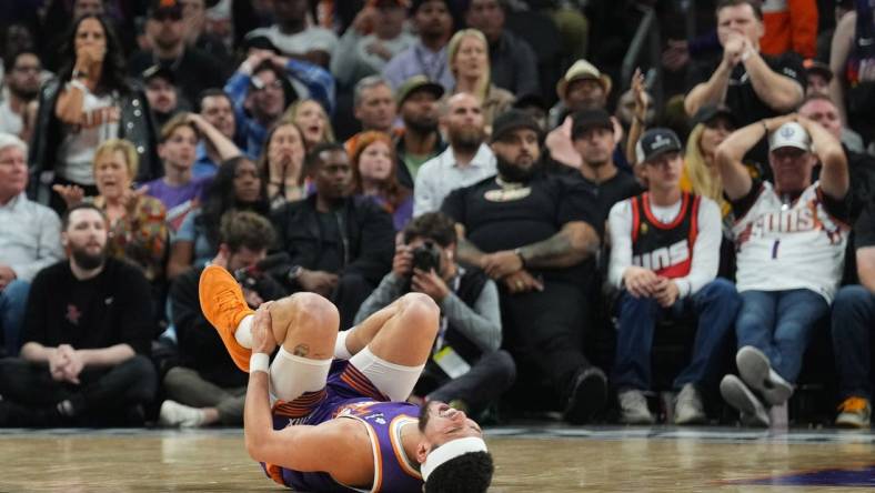 Mar 2, 2024; Phoenix, Arizona, USA; Phoenix Suns guard Devin Booker (1) reacts after being inured against the Houston Rockets during the second half at Footprint Center. Mandatory Credit: Joe Camporeale-USA TODAY Sports