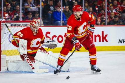 Mar 4, 2024; Calgary, Alberta, CAN; Calgary Flames defenseman MacKenzie Weegar (52) controls the puck in front of Calgary Flames goaltender Jacob Markstrom (25) during the first period against the Seattle Kraken at Scotiabank Saddledome. Mandatory Credit: Sergei Belski-USA TODAY Sports