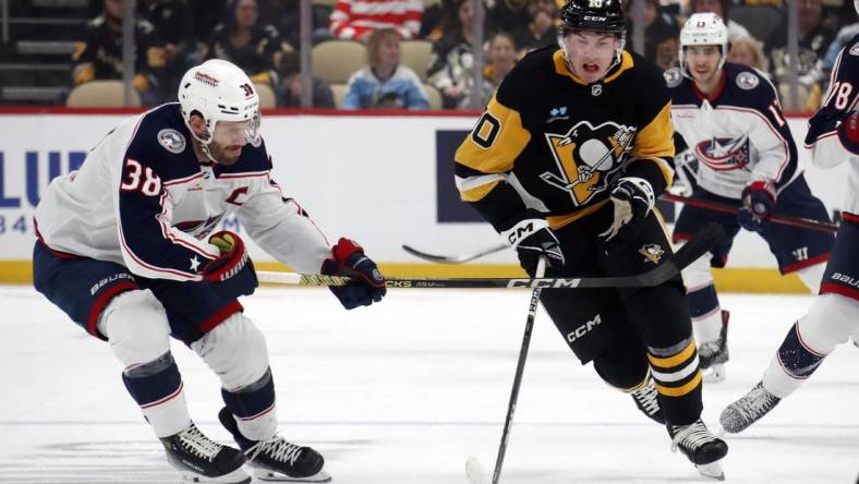 Mar 5, 2024; Pittsburgh, Pennsylvania, USA; Pittsburgh Penguins left wing Drew O'Connor (10) moves the puck up ice against Columbus Blue Jackets center Boone Jenner (38) during the first period at PPG Paints Arena. Mandatory Credit: Charles LeClaire-USA TODAY Sports