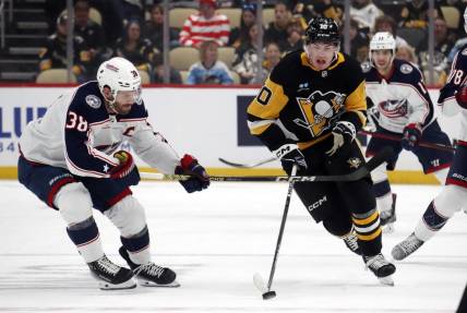 Mar 5, 2024; Pittsburgh, Pennsylvania, USA; Pittsburgh Penguins left wing Drew O'Connor (10) moves the puck up ice against Columbus Blue Jackets center Boone Jenner (38) during the first period at PPG Paints Arena. Mandatory Credit: Charles LeClaire-USA TODAY Sports