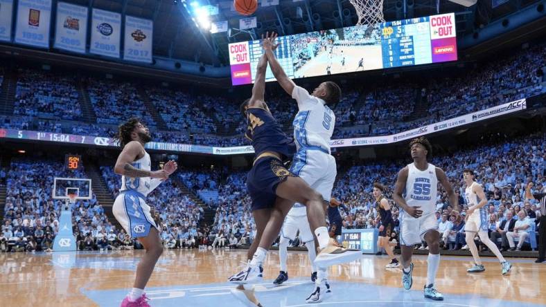 Mar 5, 2024; Chapel Hill, North Carolina, USA; Notre Dame Fighting Irish forward Kebba Njie (14) has his shot blocked by North Carolina Tar Heels forward Armando Bacot (5) during the first half at Dean E. Smith Center. Mandatory Credit: Jim Dedmon-USA TODAY Sports