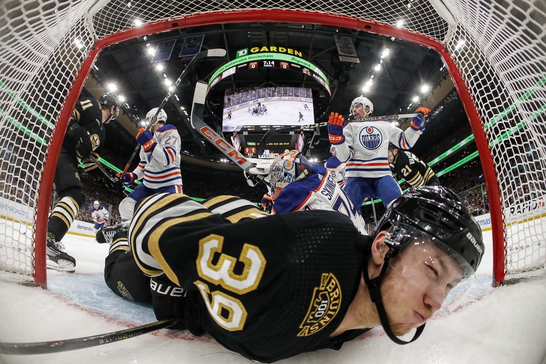 Mar 5, 2024; Boston, Massachusetts, USA; Boston Bruins center Morgan Geekie (39) is dumped into the Edmonton Oilers net during the second period at TD Garden. Mandatory Credit: Winslow Townson-USA TODAY Sports