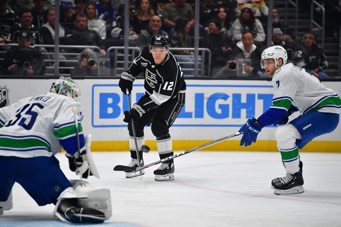 Mar 5, 2024; Los Angeles, California, USA; Los Angeles Kings left wing Trevor Moore (12) shoots on goal against Vancouver Canucks defenseman Carson Soucy (7) and goaltender Thatcher Demko (35) during the second period at Crypto.com Arena. Mandatory Credit: Gary A. Vasquez-USA TODAY Sports