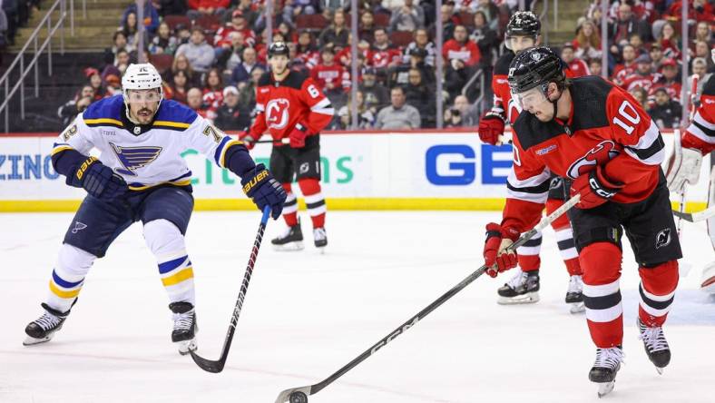 Mar 7, 2024; Newark, New Jersey, USA; New Jersey Devils right wing Alexander Holtz (10) clears the puck in front of St. Louis Blues defenseman Justin Faulk (72) during the second period at Prudential Center. Mandatory Credit: Vincent Carchietta-USA TODAY Sports