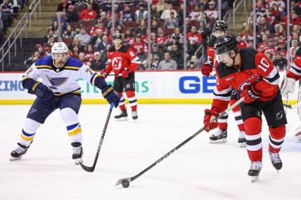 Mar 7, 2024; Newark, New Jersey, USA; New Jersey Devils right wing Alexander Holtz (10) clears the puck in front of St. Louis Blues defenseman Justin Faulk (72) during the second period at Prudential Center. Mandatory Credit: Vincent Carchietta-USA TODAY Sports