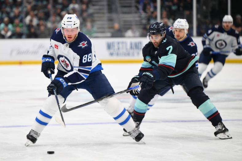 Mar 8, 2024; Seattle, Washington, USA; Winnipeg Jets defenseman Nate Schmidt (88) advances the puck while defended by Seattle Kraken right wing Jordan Eberle (7) during the first period at Climate Pledge Arena. Mandatory Credit: Steven Bisig-USA TODAY Sports