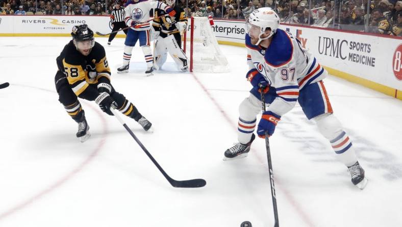 Mar 10, 2024; Pittsburgh, Pennsylvania, USA;  Edmonton Oilers center Connor McDavid (97) moves the puck against the Pittsburgh Penguins defenseman Kris Letang (58) during the second period at PPG Paints Arena. Mandatory Credit: Charles LeClaire-USA TODAY Sports