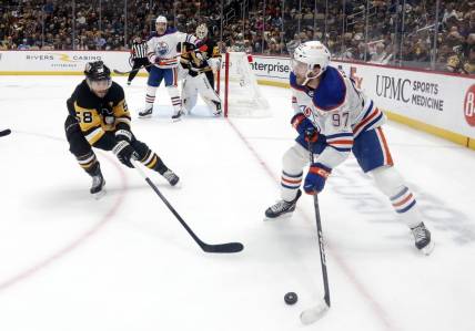 Mar 10, 2024; Pittsburgh, Pennsylvania, USA;  Edmonton Oilers center Connor McDavid (97) moves the puck against the Pittsburgh Penguins defenseman Kris Letang (58) during the second period at PPG Paints Arena. Mandatory Credit: Charles LeClaire-USA TODAY Sports