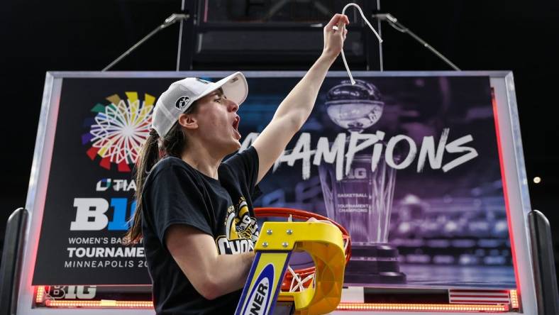 Mar 10, 2024; Minneapolis, MN, USA; Iowa Hawkeyes guard Caitlin Clark (22) cuts a piece off the net after the game against the Nebraska Cornhuskers at Target Center. Mandatory Credit: Matt Krohn-USA TODAY Sports