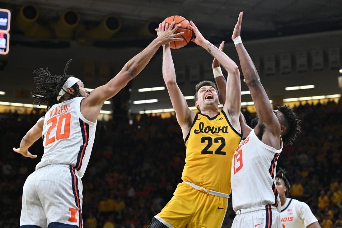 Mar 10, 2024; Iowa City, Iowa, USA; Iowa Hawkeyes forward Payton Sandfort (20) is defended by Illinois Fighting Illini forward Ty Rodgers (20) and forward Quincy Guerrier (13) during the second half at Carver-Hawkeye Arena. Mandatory Credit: Jeffrey Becker-USA TODAY Sports