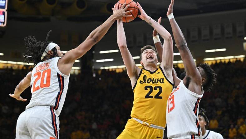 Mar 10, 2024; Iowa City, Iowa, USA; Iowa Hawkeyes forward Payton Sandfort (20) is defended by Illinois Fighting Illini forward Ty Rodgers (20) and forward Quincy Guerrier (13) during the second half at Carver-Hawkeye Arena. Mandatory Credit: Jeffrey Becker-USA TODAY Sports