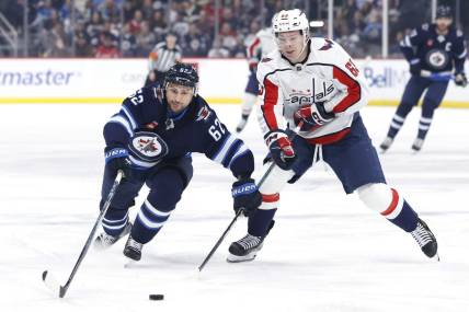 Mar 11, 2024; Winnipeg, Manitoba, CAN; Winnipeg Jets right wing Nino Niederreiter (62) and Washington Capitals left wing Ivan Miroshnichenko (63) chase after the puck in the first period at Canada Life Centre. Mandatory Credit: James Carey Lauder-USA TODAY Sports