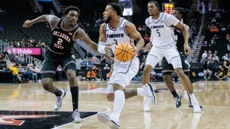 Mar 12, 2024; Kansas City, MO, USA; UCF Knights guard Darius Johnson (3) drives to the basket around Oklahoma State Cowboys forward Eric Dailey Jr. (2) during the first half at T-Mobile Center. Mandatory Credit: William Purnell-USA TODAY Sports