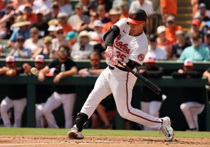 Mar 12, 2024; Sarasota, Florida, USA; Baltimore Orioles catcher Adley Rutschman (35) hits a RBI single during the second inning against the Tampa Bay Rays at Ed Smith Stadium. Mandatory Credit: Kim Klement Neitzel-USA TODAY Sports