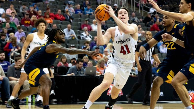 Cincinnati Bearcats guard Simas Lukosius (41) drives to the basket between West Virginia Mountaineers defenders in the first half of the Big 12 Conference tournament between Cincinnati Bearcats and West Virginia Mountaineers at T-Mobile Center in Kansas City, Mo., on Tuesday, March 12, 2024.