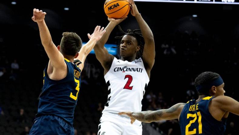 Cincinnati Bearcats guard Jizzle James (2) hits a 3-point basket as West Virginia Mountaineers guard Kerr Kriisa (3) defends in the first half of the Big 12 Conference tournament between Cincinnati Bearcats and West Virginia Mountaineers at T-Mobile Center in Kansas City, Mo., on Tuesday, March 12, 2024.