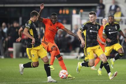 Mar 12, 2024; Columbus, OH, USA;  Columbus Crew defender Yevhen Cheberko (21) kicks the ball from Houston Dynamo forward Ibrahim Aliyu (18) during the second half of the Concacaf Champions Cup soccer game at Lower.com Field. Mandatory Credit: Adam Cairns-USA TODAY Sports