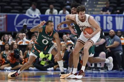 Mar 12, 2024; Washington, D.C., USA; Boston College Eagles forward Quinten Post (12) drives to the basket as Miami (Fl) Hurricanes guard Matthew Cleveland (0) and Hurricanes forward Norchad Omier (15) defend in the first half at Capital One Arena. Mandatory Credit: Geoff Burke-USA TODAY Sports