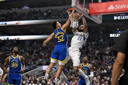 Mar 13, 2024; Dallas, Texas, USA; Dallas Mavericks center Daniel Gafford (21) dunks the ball past Golden State Warriors forward Trayce Jackson-Davis (32) during the first quarter at the American Airlines Center. Mandatory Credit: Jerome Miron-USA TODAY Sports