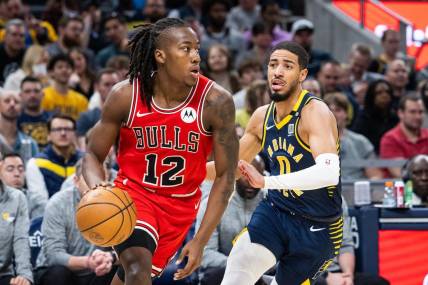 Mar 13, 2024; Indianapolis, Indiana, USA; Chicago Bulls guard Ayo Dosunmu (12) dribbles the ball while Indiana Pacers guard Tyrese Haliburton (0) defends in the first half at Gainbridge Fieldhouse. Mandatory Credit: Trevor Ruszkowski-USA TODAY Sports