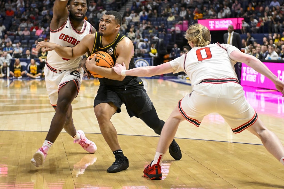 Mar 13, 2024; Nashville, TN, USA;  Missouri Tigers guard Nick Honor (10) splits Georgia Bulldogs guard Blue Cain (0) and forward Jalen DeLoach (23) during the first half at Bridgestone Arena. Mandatory Credit: Steve Roberts-USA TODAY Sports