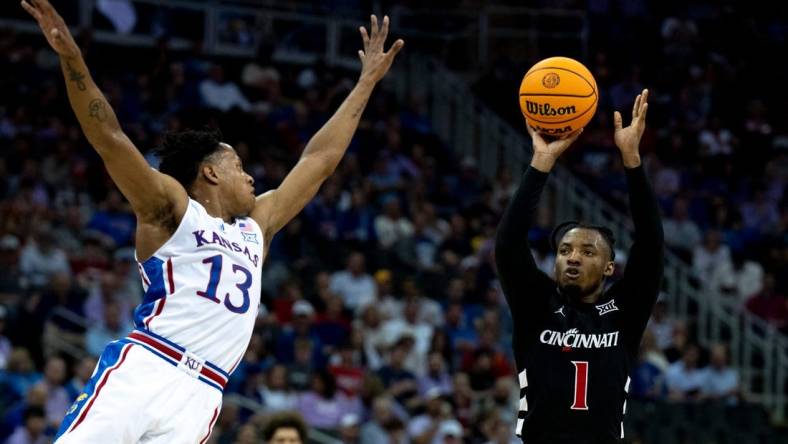 Cincinnati Bearcats guard Day Day Thomas (1) hits a 3-point basket as Kansas Jayhawks guard Elmarko Jackson (13) defends in the first half of the Big 12 Conference tournament game between Cincinnati Bearcats and Kansas Jayhawks at T-Mobile Center in Kansas City, Mo., on Wednesday, March 13, 2024.