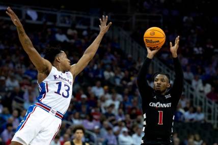 Cincinnati Bearcats guard Day Day Thomas (1) hits a 3-point basket as Kansas Jayhawks guard Elmarko Jackson (13) defends in the first half of the Big 12 Conference tournament game between Cincinnati Bearcats and Kansas Jayhawks at T-Mobile Center in Kansas City, Mo., on Wednesday, March 13, 2024.