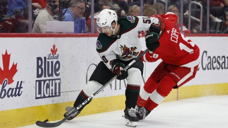 Mar 14, 2024; Detroit, Michigan, USA;  Arizona Coyotes defenseman Sean Durzi (50) and Detroit Red Wings center Andrew Copp (18) battle for the puck in the second period at Little Caesars Arena. Mandatory Credit: Rick Osentoski-USA TODAY Sports