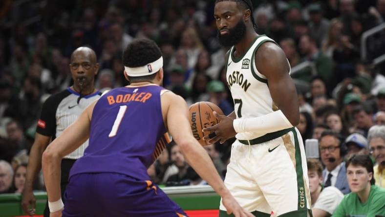 Mar 14, 2024; Boston, Massachusetts, USA;  Boston Celtics guard Jaylen Brown (7) controls the ball while Phoenix Suns guard Devin Booker (1) defends during the second half at TD Garden. Mandatory Credit: Bob DeChiara-USA TODAY Sports