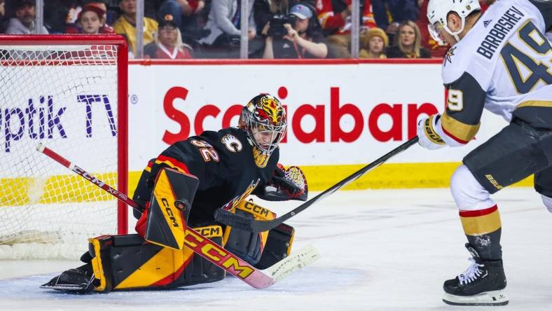 Mar 14, 2024; Calgary, Alberta, CAN; Calgary Flames goaltender Dustin Wolf (32) makes a save against Vegas Golden Knights center Ivan Barbashev (49) during the third period at Scotiabank Saddledome. Mandatory Credit: Sergei Belski-USA TODAY Sports