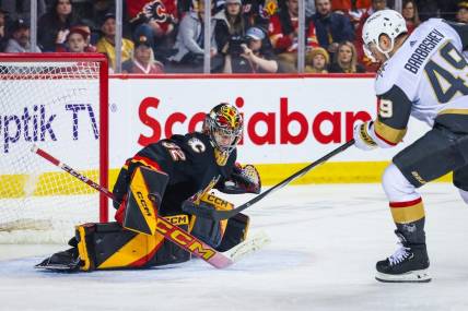 Mar 14, 2024; Calgary, Alberta, CAN; Calgary Flames goaltender Dustin Wolf (32) makes a save against Vegas Golden Knights center Ivan Barbashev (49) during the third period at Scotiabank Saddledome. Mandatory Credit: Sergei Belski-USA TODAY Sports