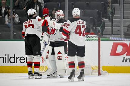 Mar 14, 2024; Dallas, Texas, USA; New Jersey Devils defenseman Luke Hughes (43) and center Curtis Lazar (42) and goaltender Jake Allen (34) celebrate on the ice after the Devils defeat the Dallas Stars at the American Airlines Center. Mandatory Credit: Jerome Miron-USA TODAY Sports