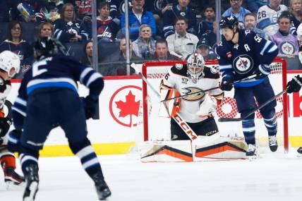 Mar 15, 2024; Winnipeg, Manitoba, CAN; Anaheim Ducks goalie John Gibson (36) makes a save on a shot by Winnipeg Jets defenseman Dylan DeMelo (2) during the first period at Canada Life Centre. Mandatory Credit: Terrence Lee-USA TODAY Sports