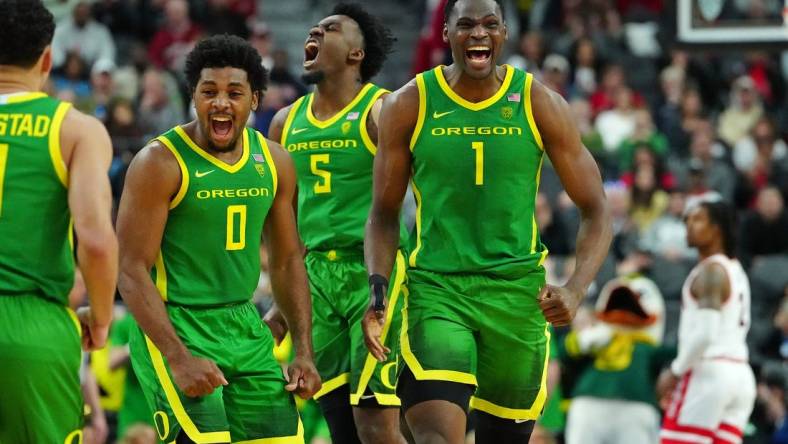 Mar 15, 2024; Las Vegas, NV, USA; Oregon Ducks center N'Faly Dante (1) celebrates with Oregon Ducks guard Kario Oquendo (0), and Oregon Ducks guard Jermaine Couisnard (5) after making a play against the Arizona Wildcats during the second half at T-Mobile Arena. Mandatory Credit: Stephen R. Sylvanie-USA TODAY Sports