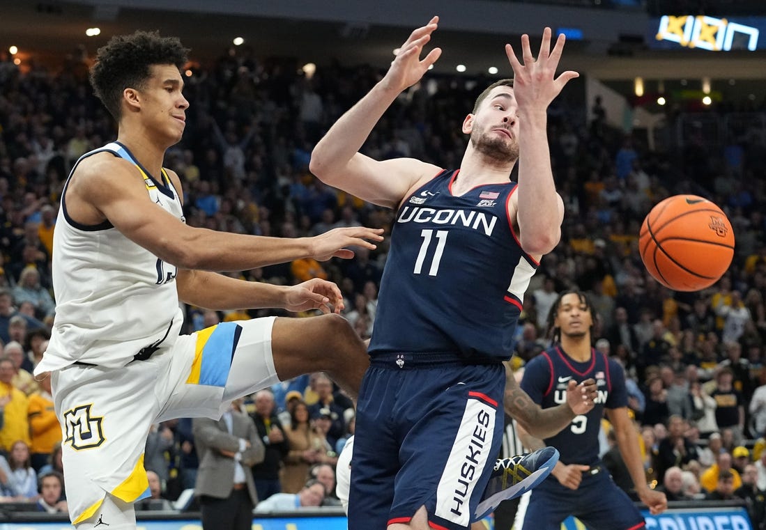 Marquette's Oso Ighodaro (13) swats the ball away from UConn forward Alex Karaban (11) during the second half of their game Wednesday, March 6, 2024 at Fiserv Forum in Milwaukee, Wisconsin. UConn beat Marquette 74-67.